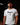 Adult baseball athlete wearing the white Bangerz Cutternation tri-blend tee in a dark batting facility