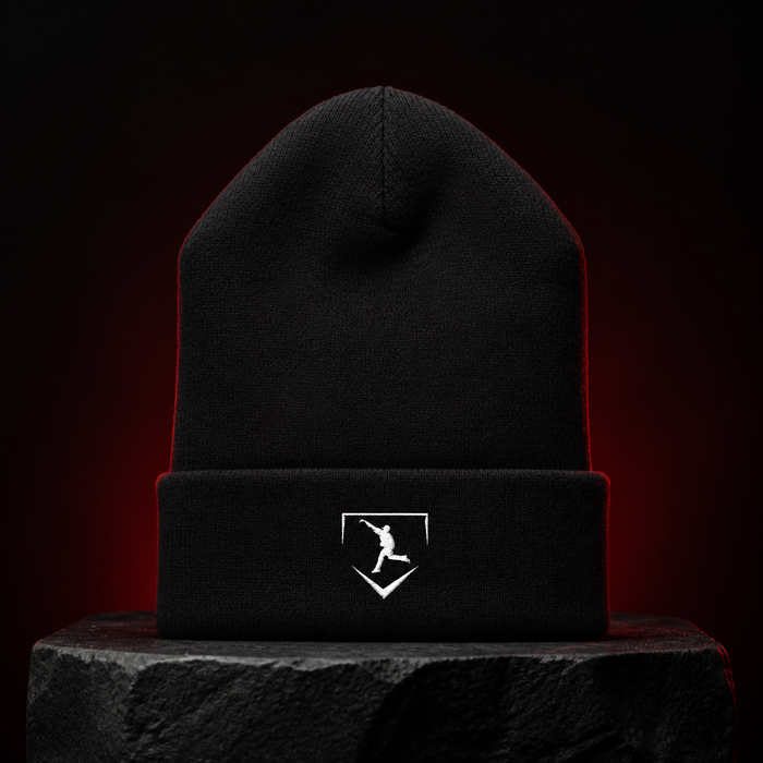Cutternation black beanie with centered white home plate pitcher logo on a dark studio pedestal