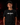 Youth baseball player wearing a black Cutternation Qué Raro T-shirt in an indoor batting cage